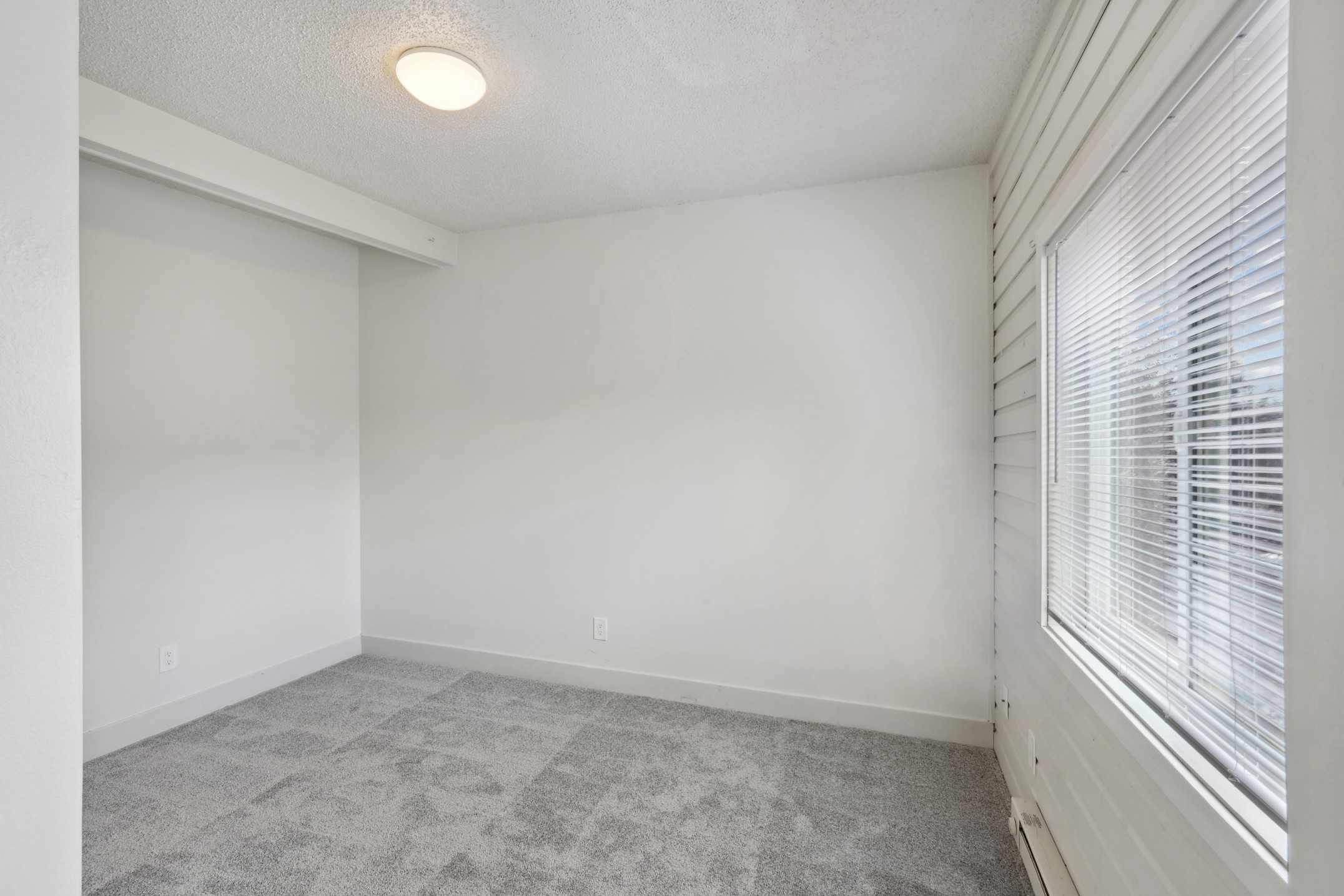 Bedroom with large window and wall to wall carpeting at Flats on 2nd